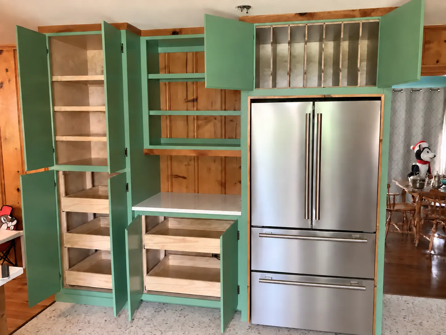 Green pantry cabinets open to show integrated storage