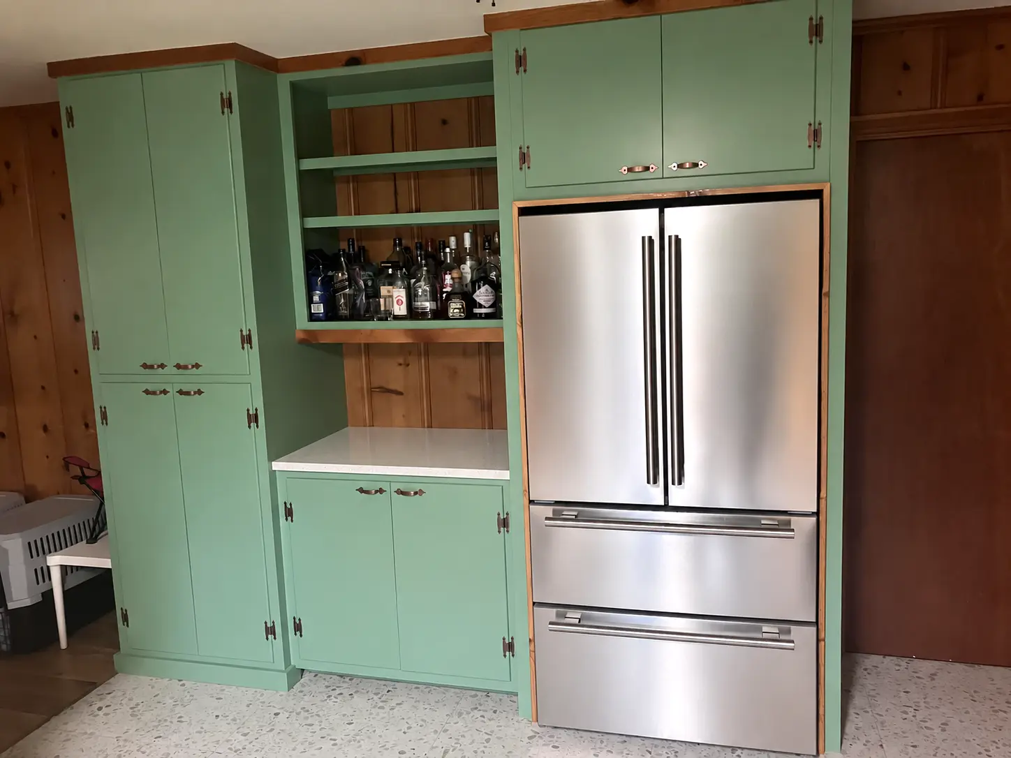 Green inset pantry cabinetry surrounding a clean stainless-steel refrigerator