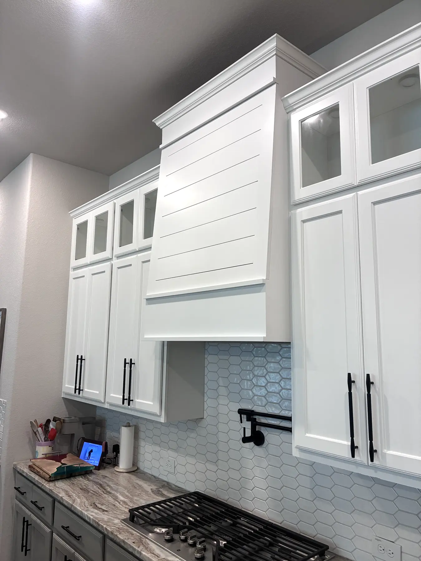 Completed custom white wood hood integrated with the surrounding kitchen cabinetry
