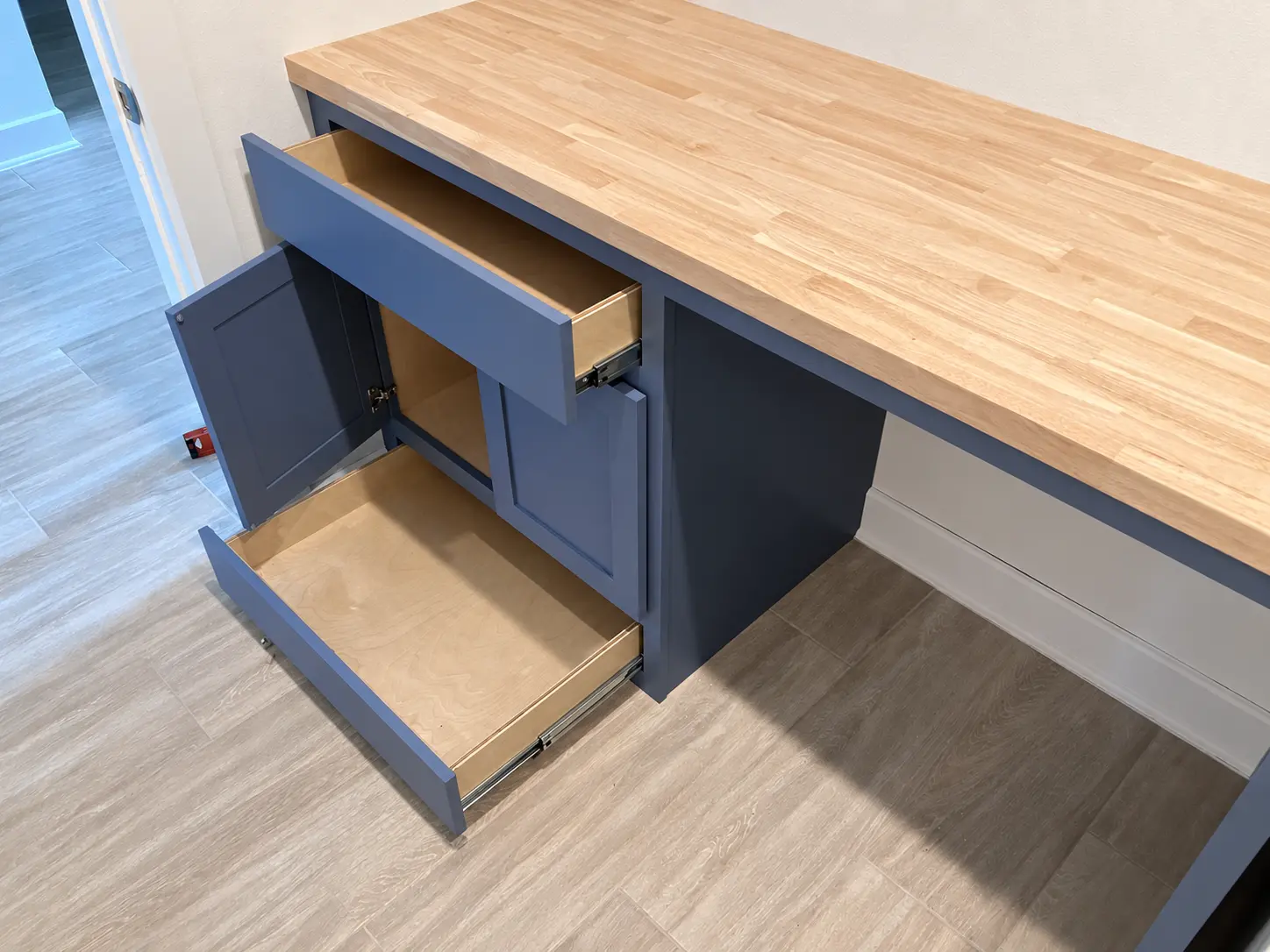 Open drawers and cabinet storage beneath a clear butcher-block laundry-room worktop