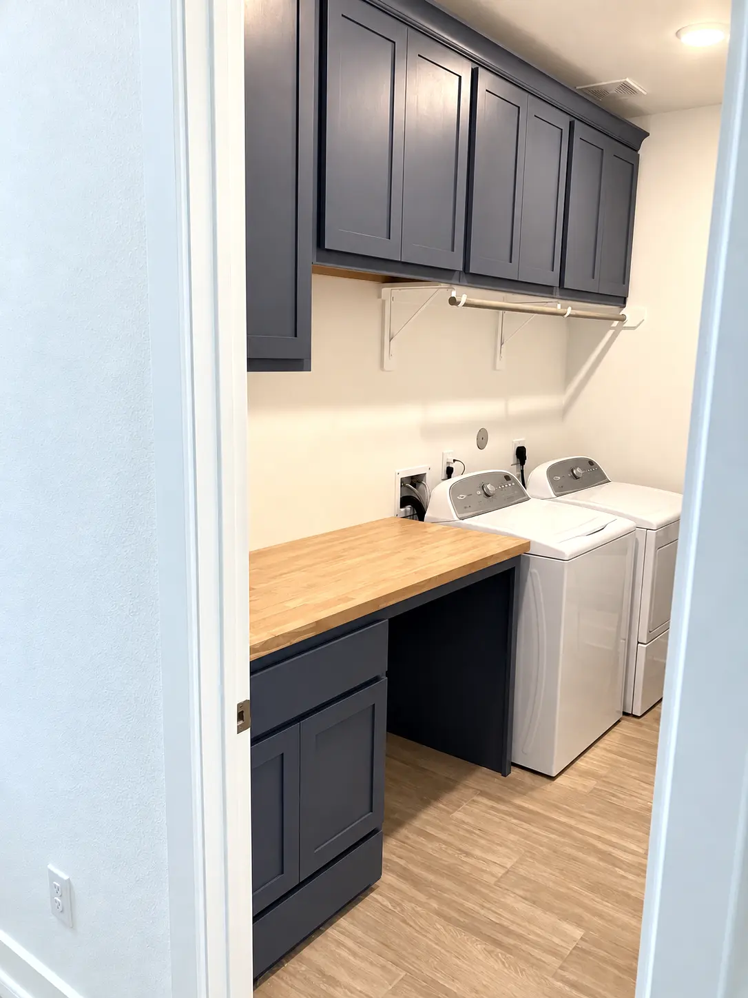 Full view of blue laundry-room cabinetry, upper cabinets, butcher-block worktop, washer and dryer
